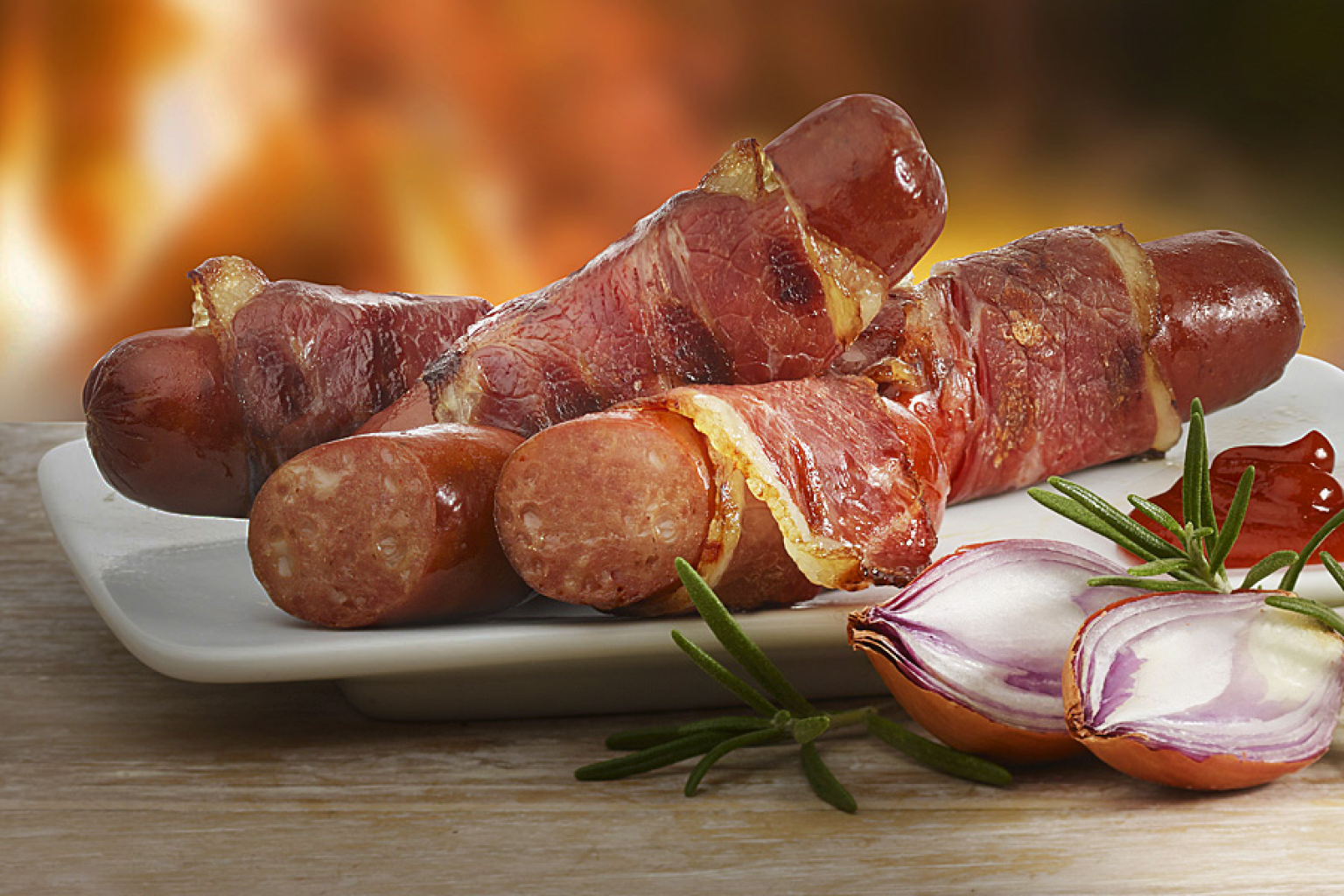 Berner Würstchen auf Holztisch vor offenem Feuer